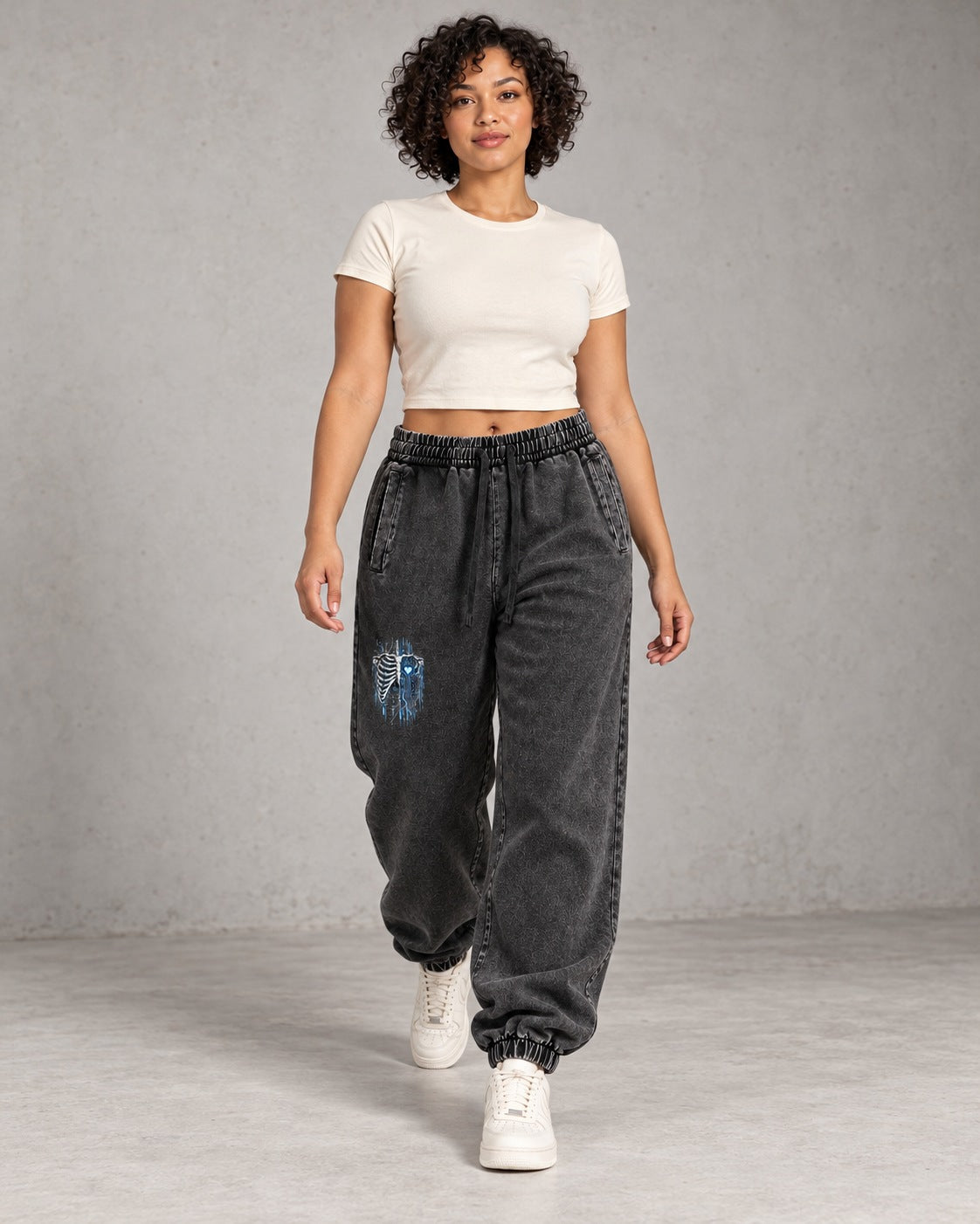 AI model visualization of snow-washed black EvoCore Bone Circuit joggers in a walking pose, showing the small blue and bone graphic on the right front thigh.