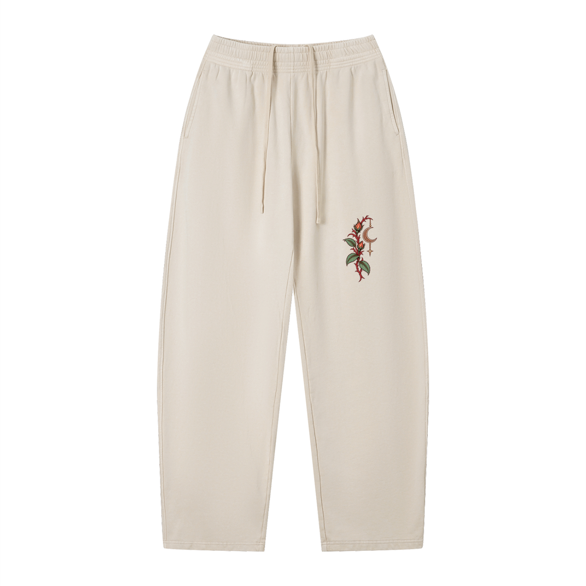 Front of EvoCore Thornlight Conservatory Apricot sweatpants with red thorned stems, green leaves and a crescent on the left leg.