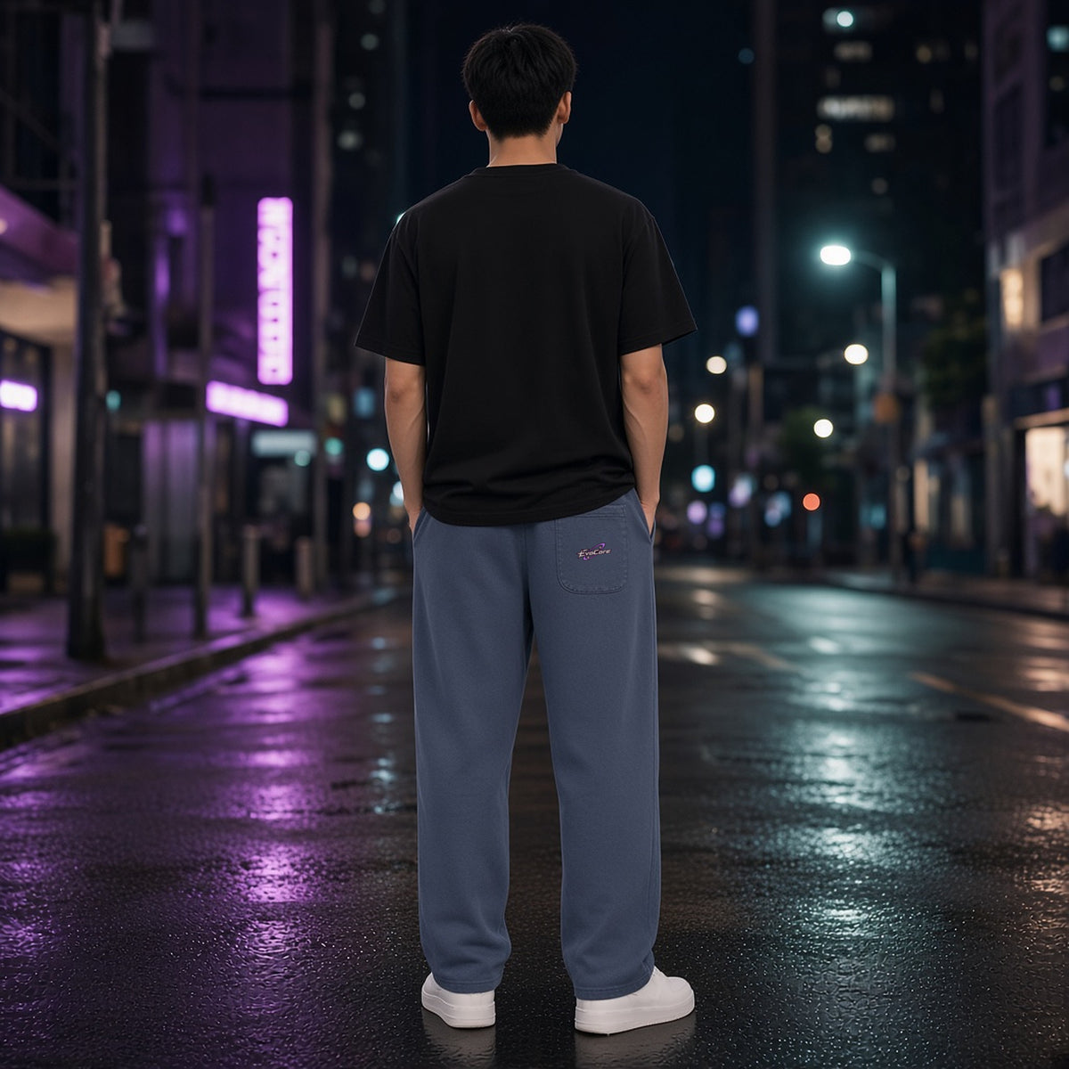 Back view of EvoCore Ghost Cache Navy Blue loose sweatpants worn on a night city street, showing the orbit logo on the rear patch pocket.