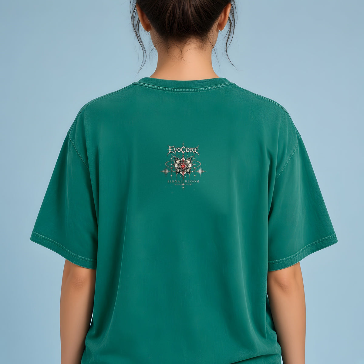 Back view of the Dark Green EvoCore Signal Bloom Tee showing the back print, powder-blue studio.