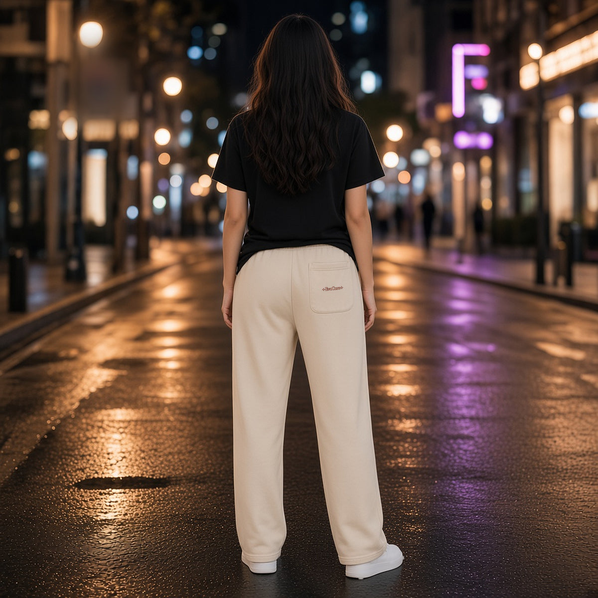 Back view of EvoCore Thornlight Conservatory Apricot loose sweatpants on a night street, showing the EvoCore wordmark on the rear patch pocket.