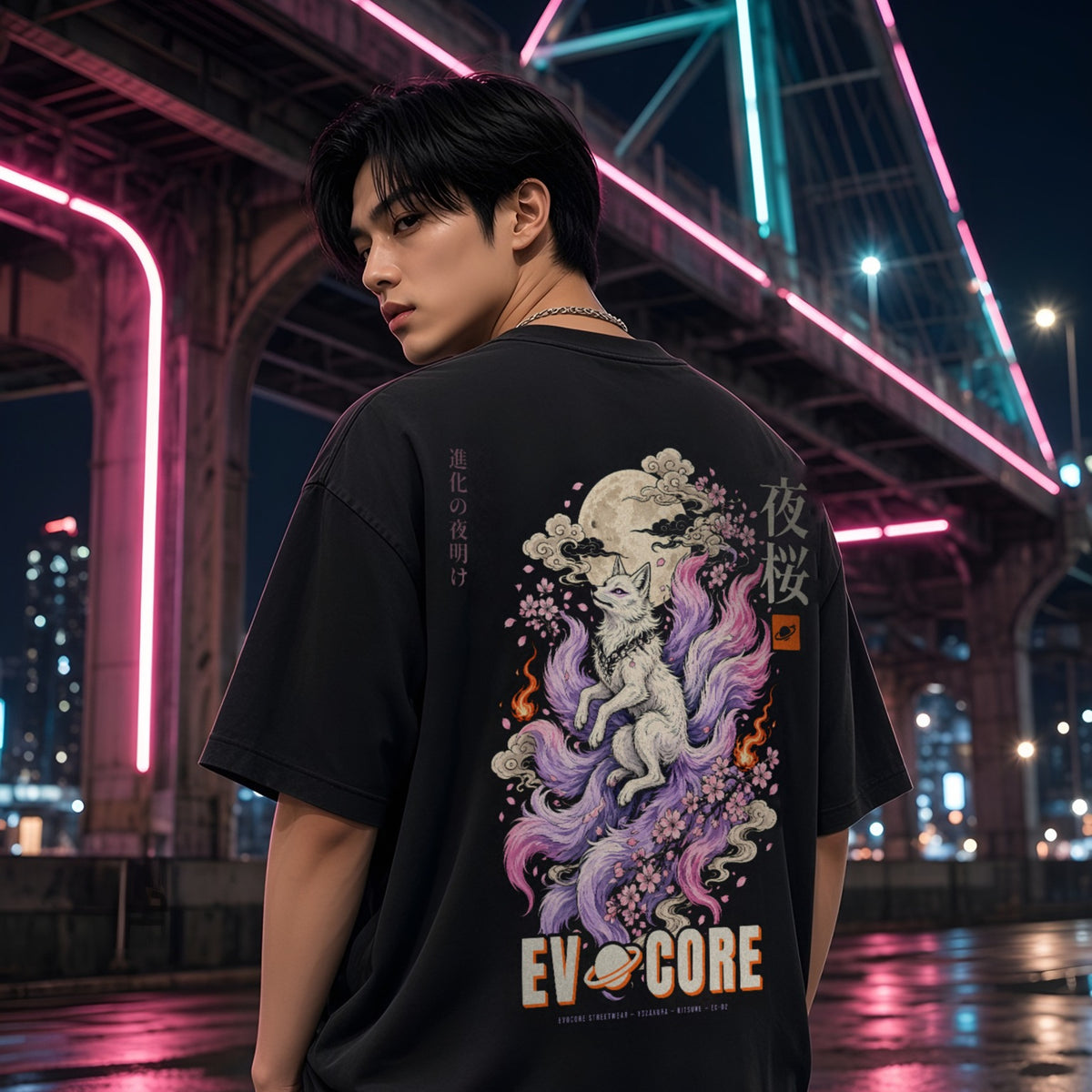 Over-the-shoulder look at the oversized EvoCore Yozakura Tee under a neon-lit bridge, full-back kitsune and cherry blossom print